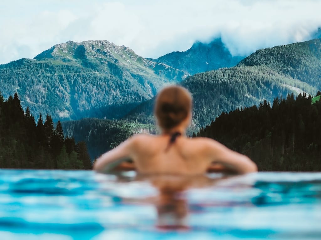 Lady enjoying the view of mountains and a pool, capturing a serene and picturesque moment.